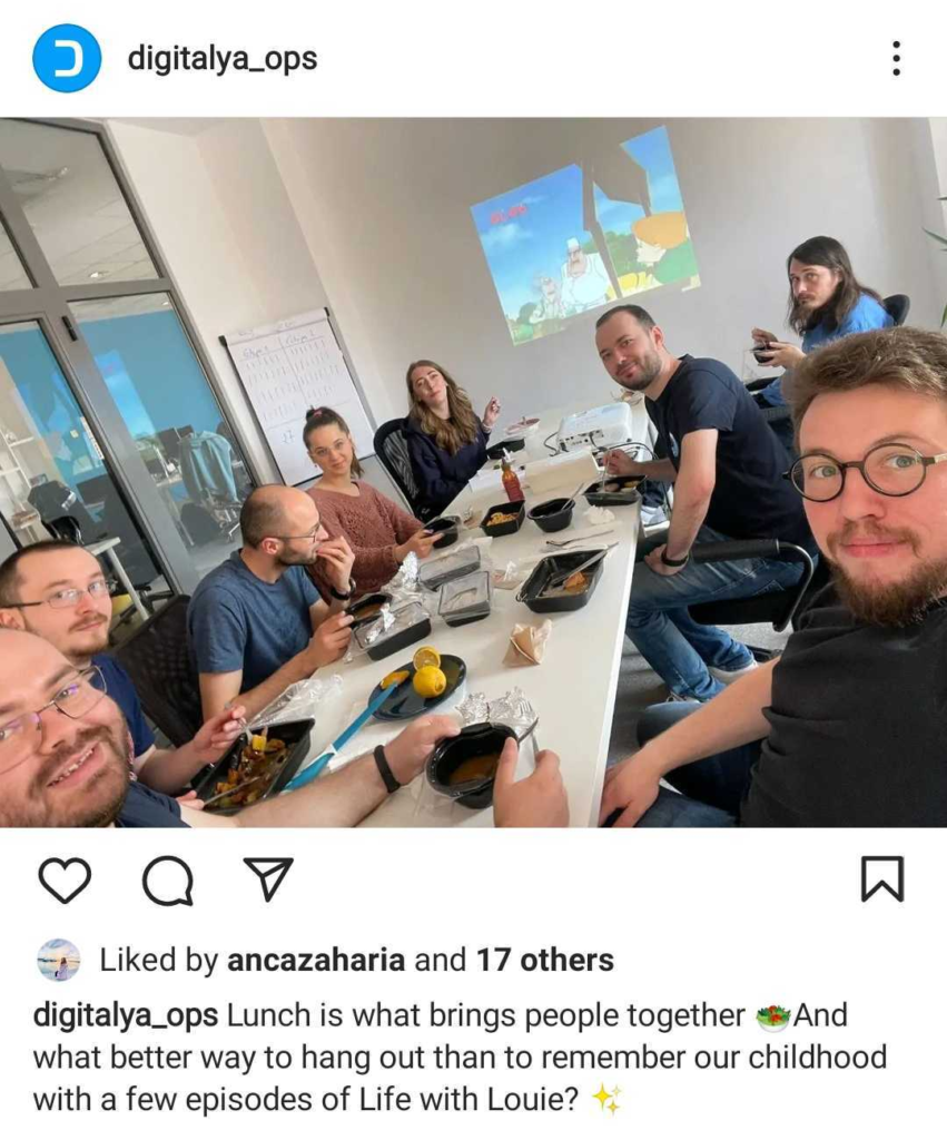 A part of the team having lunch in an office with a cartoon projected on the wall, appearing to enjoy a casual, communal meal.
